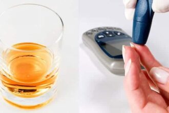 Glass of alcohol on a table and person checking their blood sugar