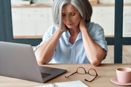 Woman in front of laptop holds her head in her hands.